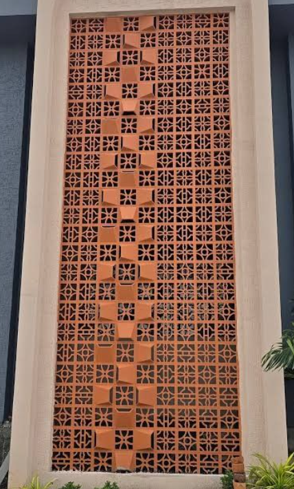 Tall terracotta breeze block facade framed by a modern building opening